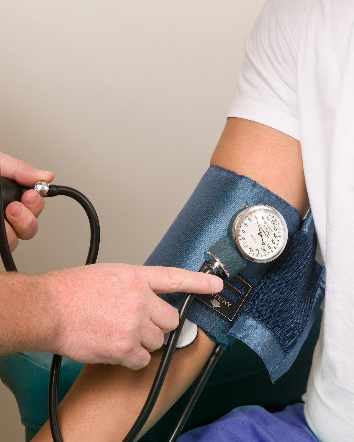 A clinician's hands on a blood pressure cuff wrapped around a patient's arm